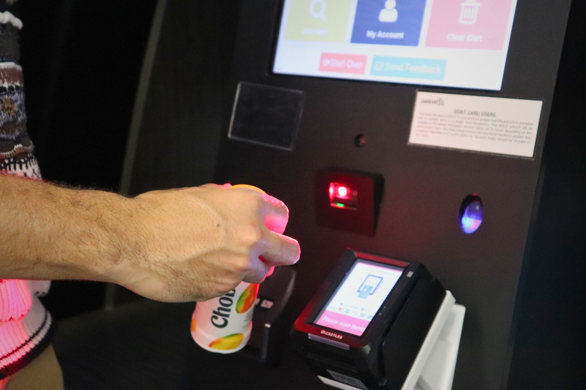 A customer scanning a drink at the market checkout